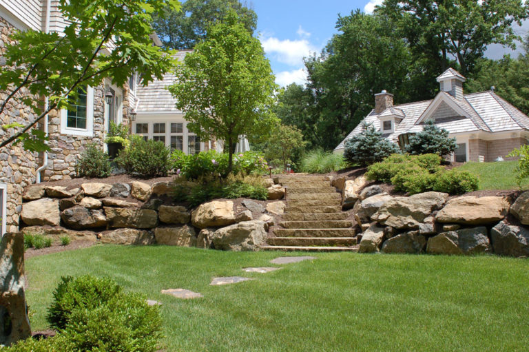 A garden with stairs and rocks in the background.